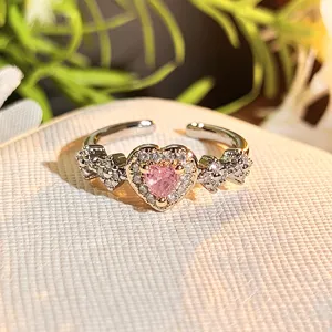 Detailed close-up of a stunning heart-shaped pink zircon open ring with delicate side crystals.