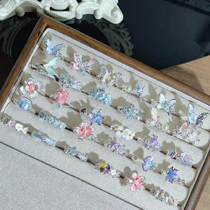 Detailed view of forest-style colorful enamel flower and butterfly zircon open rings, stackable.
