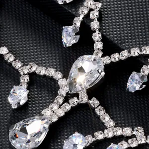 Close-up detail of sparkling rhinestone tassel mask, glittering crystal face chain accessory.