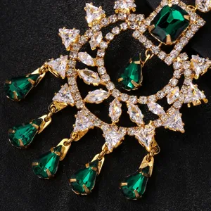 Gros plan détaillé de coiffure maang tikka dorée avec cristaux brillants et pierres vertes.
