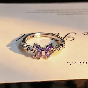 Close-up detail of silver open ring featuring a sparkling purple zircon butterfly shape.