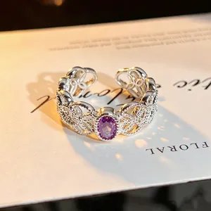 Detail shot of a hollow floral open ring featuring a purple oval stone, elegant and trendy jewelry.