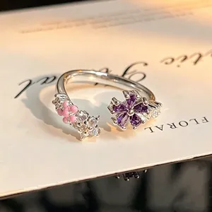 Detailed shot of an open silver ring with purple zircon flower and pink stones, elegant jewelry.