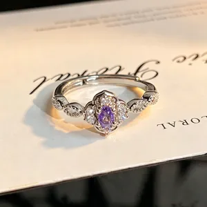 Close-up detail of silver open ring featuring a purple oval zircon with floral micro-set stones.