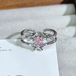 Detail view of silver open ring featuring a sparkling pink zircon center stone and bow design.