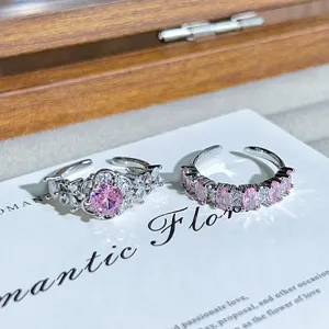 Close-up detail of sparkling pink cubic zirconia cluster and eternity rings in silver tone.