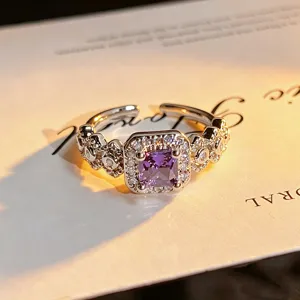 Detailed shot of open ring featuring a square purple zircon and hollow floral heart pavé design.