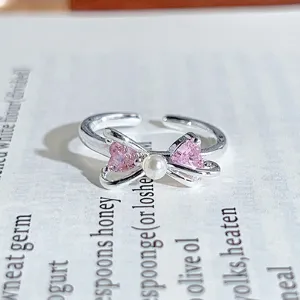Close-up view of the silver open ring showcasing a bow, pink heart zirconia, and a pearl.