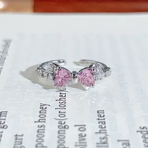 Close-up detail of the sparkling pink heart bow ring, silver metal band, elegant shine.