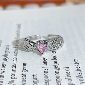 Close-up of a silver open ring featuring a pink heart-shaped cubic zirconia and wing details.