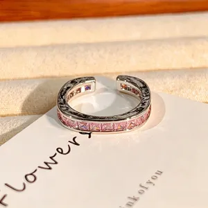 Gedetailleerd close-upoverzicht van een open ring met roze zirkonia en stijlvolle textuur.