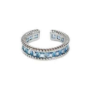 Gedetailleerde close-up van de open zilveren ring met blauwe zirkonia en gedraaide randen.