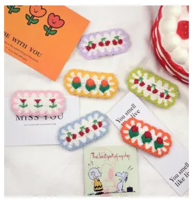 Detailed close-up of colorful crochet flower and cherry hair clips, cute handmade design.