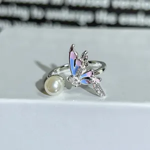 Close-up detail of silver open ring with pearl and colorful enamel butterfly zircon decor.