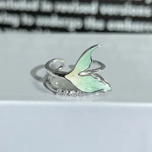 Close-up detail view of silver open ring featuring green enamel tail and sparkling zirconia stones.