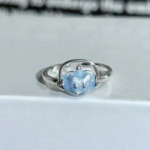 Detailed close-up of a silver adjustable ring featuring a cute glittery blue headphone character.