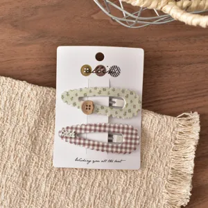 Primo piano dettagliato di mollette per capelli floreali e a quadri su una carta.
