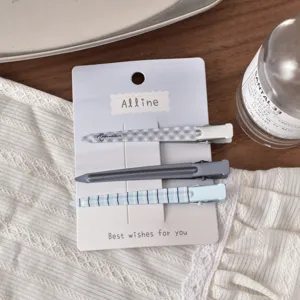 Detailed view of blue checkered and solid hair clips set on white display card.