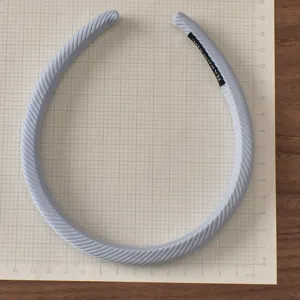 Close-up detail of light blue striped fabric headband with handmade label on grid paper.