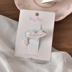 Graziosa molletta per capelli a cuore in acrilico con motivo floreale e strass brillanti.