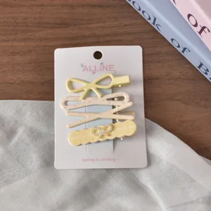 Detail shot of cute pastel hair clips set featuring bow and floral designs on backing card.
