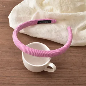 Close-up of the pink striped headband detail, showing soft fabric texture, narrow edge and handmade label.