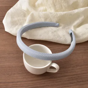 Close-up detail of light blue striped narrow headband on tabletop, minimalist style
