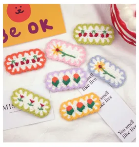 Detailed view of handmade knitted hair clips featuring cute cherry and floral embroidery designs.