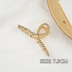 Dettaglio del fermaglio per capelli in metallo dorato, design intrecciato elegante, presa forte.