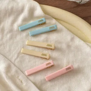 Nahaufnahme minimalistischer Acetat-Haarspangen in Pastellfarben mit Entenschnabel-Design.