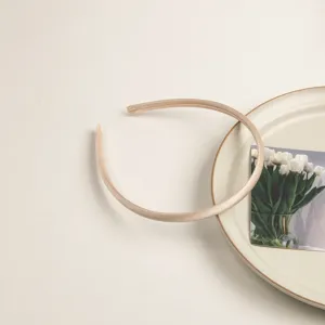 Vue detaillee d'un serre-tete fin en satin de couleur champagne, accessoire elegant chic.