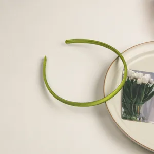 Détail de serre-tête en satin vert, design minimaliste, parfait pour le style et les cheveux.