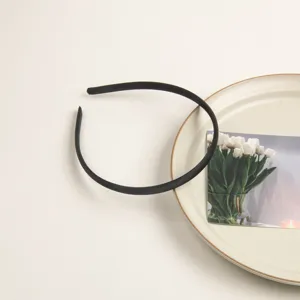 Détail en gros plan d'un serre-tête en satin noir minimaliste, accessoire de coiffure chic.