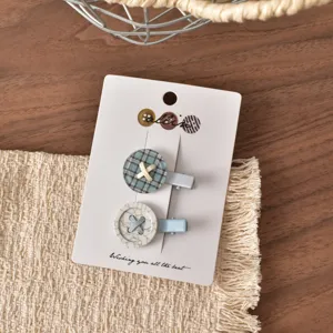 Set di fermagli per capelli a bottone con motivi a quadri e marmo su carta bianca.