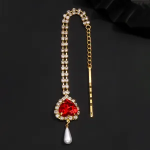 Detailaufnahme einer glamourösen goldenen Strass-Stirnkette mit rotem Herz-Edelstein.