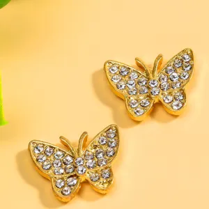 Dettaglio adesivo petto farfalla con strass, accessorio dorato squisito per abito elegante.
