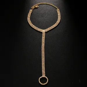 Dettaglio catena da piede dorata con strass, gioiello da spiaggia estivo scintillante.