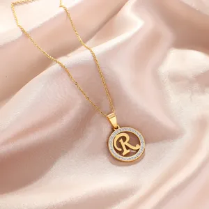 Close-up detail of the elegant gold letter R pendant necklace with sparkling rhinestone circle.