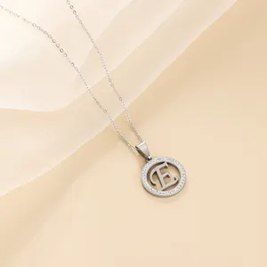 Detailed view of silver letter E pendant necklace with rhinestone paved circular charm.