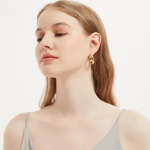 Close-up view of a model wearing minimalist thick gold hoop earrings, elegant fashion jewelry.
