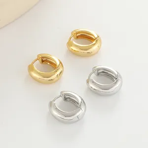 Detailed view of trendy chunky gold and silver small hoop earrings, minimalist fashion jewelry.