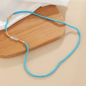 Turquoise heishi bead necklace detail featuring love letter charms and gold accents.