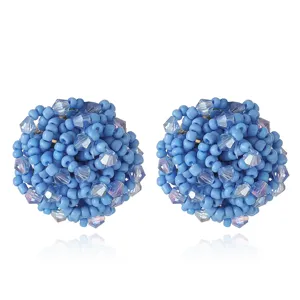 Gros plan de boucles d'oreilles boules en perles bleues faites main, texture fine.