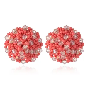 Gros plan détail de boules d'oreilles en perles roses et cristal, design géométrique.