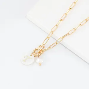 Goldene Büroklammer-Kette mit weißem Muschel-Buchstaben-T-Anhänger und zarten Perlendetails.
