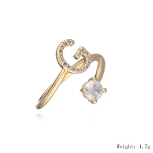 Vergoldeter Offener Ring mit glitzerndem Buchstaben G und einzelnem Zirkoniastein.