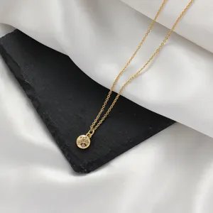 Vergoldete filigrane Halskette mit einem kleinen runden Kristallanhänger im minimalistischen Stil.