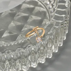 Detailaufnahme eines vergoldeten Buchstaben Rings mit funkelnden Zirkoniasteinen.