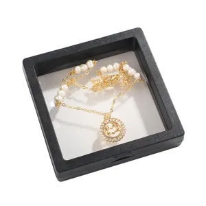 Gold chain necklace with pearls and rhinestone heart hand pendant displayed in black floating box.
