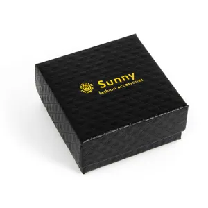 Black textured jewelry gift box detail shot, elegant packaging for rings and earrings.